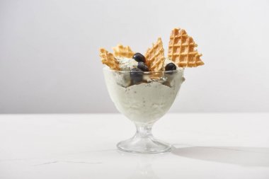 delicious pistachio ice cream with waffles and blueberries isolated on grey clipart