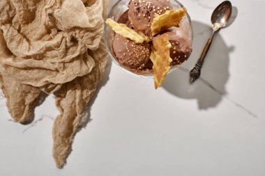 mermer gri arka planda kahverengi bez ve kaşık yakın waffle ile kase lezzetli çikolata dondurma üst görünümü