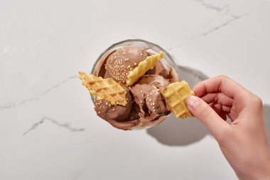 mermer gri arka planda kase lezzetli çikolata dondurma yakın kadın tutarak waffle kırpılmış görünümü