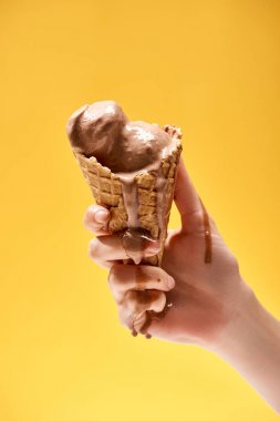 sarı üzerinde izole çıtır waffle koni lezzetli erimiş çikolata dondurma tutan kadın kırpılmış görünümü