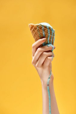 sarı üzerinde izole çıtır waffle koni lezzetli erimiş mavi dondurma tutan kadın kırpılmış görünümü