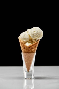 delicious vanilla ice cream in crispy waffle cone isolated on black  clipart