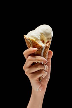 siyah üzerinde izole çıtır waffle koni eritme lezzetli vanilyalı dondurma tutan kadın kırpılmış görünümü 