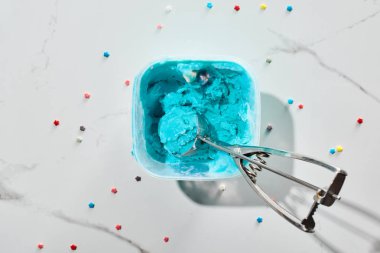mermer gri arka planda dondurma kaşığı ile kutuda Sprinkles ile lezzetli mavi dondurma üst görünümü
