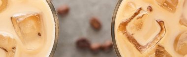 close up view of ice coffee in glasses and coffee grains on grey background, panoramic shot clipart