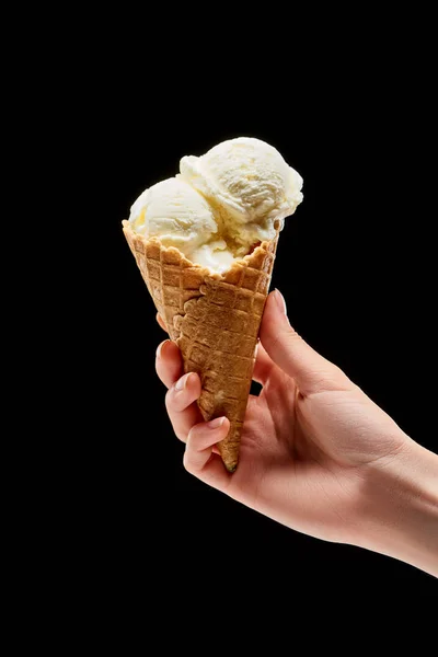 黒で分離されたサクサクワッフルコーンでおいしいバニラアイスクリームを持つ女性のトリミングビュー — ストック写真