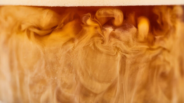 close up view of coffee mixing with white milk in glass