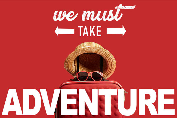 Red colorful travel bag with straw hat and sunglasses isolated on red with we must take adventure illustration