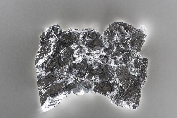 top view of glossy crumpled silver foil on grey background