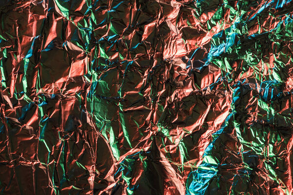 вид сверху на глянцевую скомканную фольгу с красочным отражением освещения
