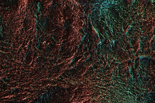 abstract background of silver textured crumpled foil with colorful illumination