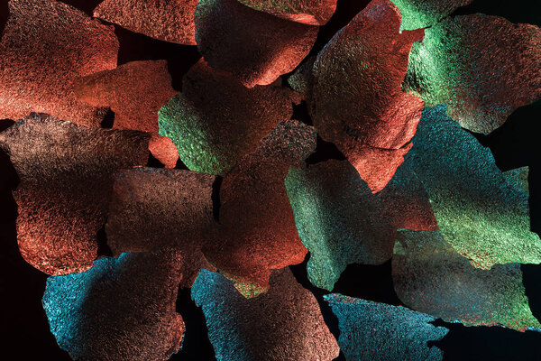абстрактный фон из рваной серебряной фольги с красочной подсветкой, изолированной на черном
