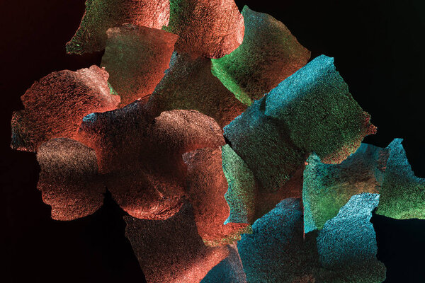 абстрактный фон из текстурированной фольги с красочной подсветкой, изолированной на черном
