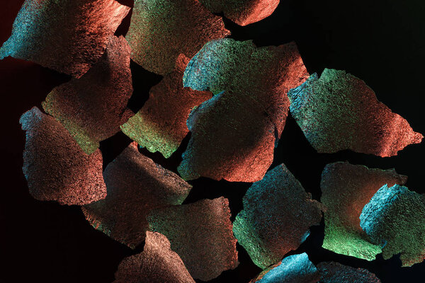 абстрактный фон из серебряной фольги с красочной подсветкой, изолированной на черном

