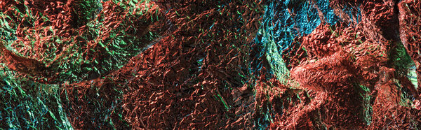 panoramic shot of abstract background of textured crumpled foil with colorful lighting