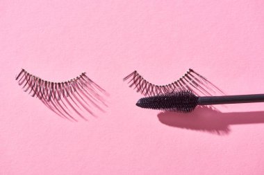 top view of false eyelashes and brush on pink background  clipart