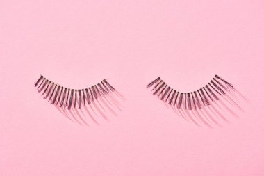 top view of false eyelashes on pink background with copy space  clipart