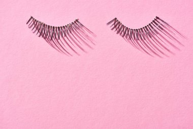 top view of false eyelashes on pink background with copy space  clipart