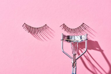 pembe arka plan üzerinde yanlış kirpik ve kirpik curler üst görünümü 