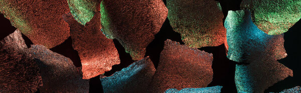 панорамный снимок абстрактного фона разорванной фольги с красочной подсветкой, изолированной на черном
