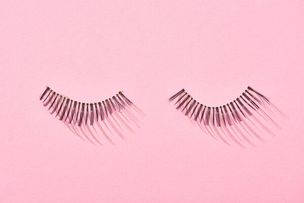 вид сверху накладных ресниц на розовом фоне с копировальным пространством
 