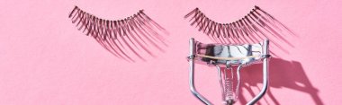 panoramic shot of false eyelashes and eyelash curler on pink background  clipart