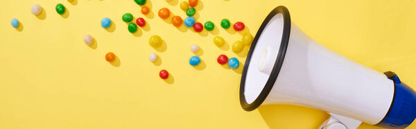 panoramic shot of loudspeaker with candies on bright and colorful background 