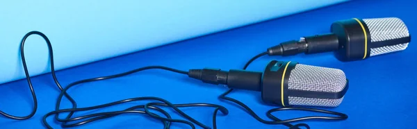 Panoramiczny Strzał Czarnych Mikrofonów Drutami Kolorowym Tle — Zdjęcie stockowe