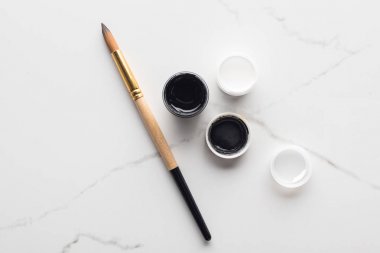 mermer beyaz yüzey üzerinde siyah ve beyaz guaj boyalar ve Paintbrush üst görünümü
