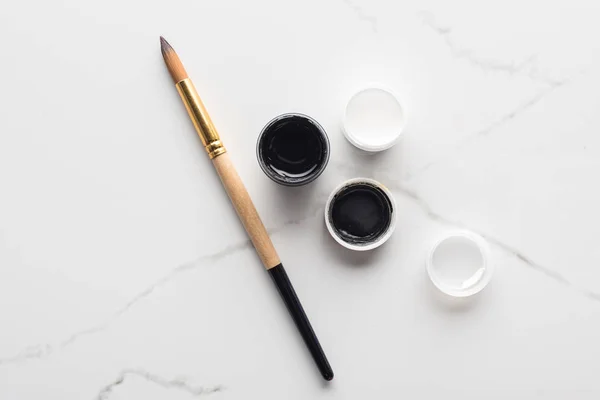 大理石白色表面上的黑白水粉和画笔的顶视图 — 图库照片