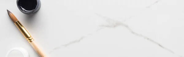 大理石の白い表面に黒と白のグアッシュ塗料とペイントブラシのトップビュー パノラマショット — ストック写真