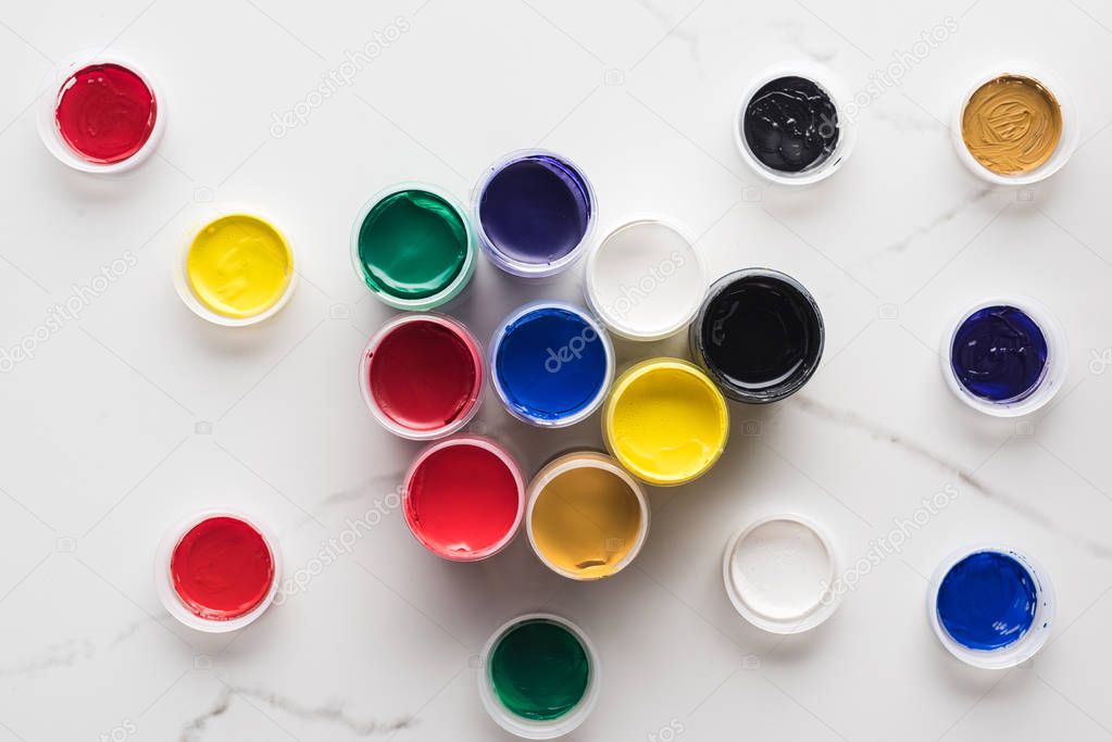 top view of multicolored gouache paints on marble white surface