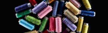 panoramic shot of bright and colorful threads isolated on black clipart