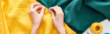 panoramic shot of seamstress sewing colorful fabric with needle on white background  clipart