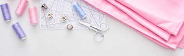 panoramic shot of fabric, sewing pattern, scissors, thimbles, bobbins and threads on white background  clipart