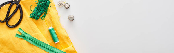 панорамный снимок молнии, ножницы, наперстки, нити, бобин, ткани на белом фоне
 