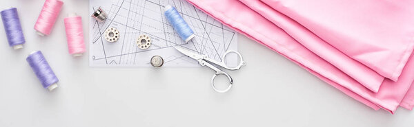 панорамный снимок ткани, узора шитья, ножниц, наперстков, косичек и нитей на белом фоне
 