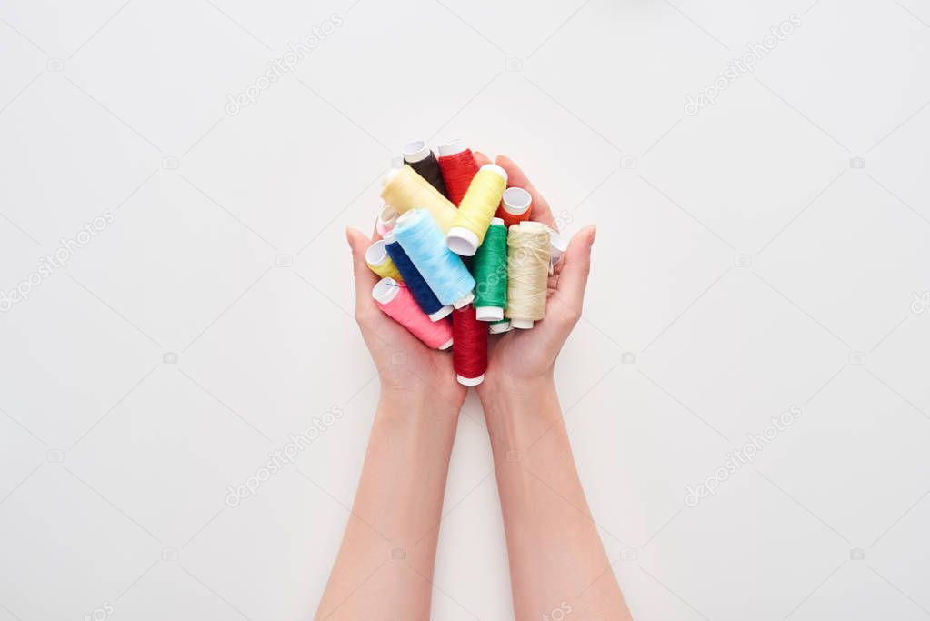 cropped view of woman holding bright and colorful threads on white background 