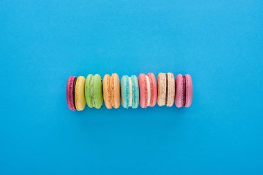 mavi parlak arka plan üzerinde çizgi de çok renkli lezzetli Fransız macaroons üst görünümü
