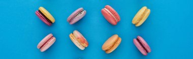 mavi parlak arka plan, panoramik çekim üzerinde tatlı çok renkli Fransız macaroons ile düz yatıyordu