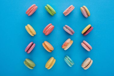 mavi parlak arka plan üzerinde tatlı çok renkli lezzetli Fransız macaroons ile düz yatıyordu
