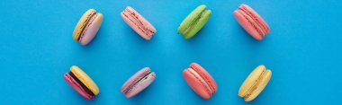 mavi parlak arka plan, panoramik çekim üzerinde tatlı çok renkli lezzetli Fransız macaroons ile düz yatıyordu