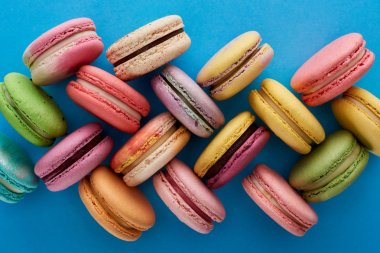 mavi parlak arka plan üzerinde çeşitli lezzetli Fransız macaroons üst görünümü