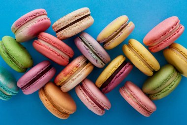 top view of assorted delicious French macaroons on blue bright background clipart
