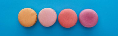 düz mavi parlak arka plan, panoramik çekim renkli lezzetli Fransız macaroons ile yatıyordu