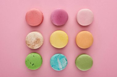 pembe arka plan üzerinde çok renkli lezzetli Fransız macaroons ile düz yatıyordu