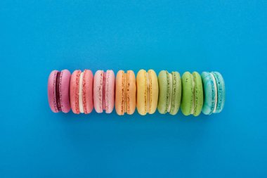 mavi parlak arka plan üzerinde doğrultusunda renkli taze lezzetli Fransız macaroons üst görünümü