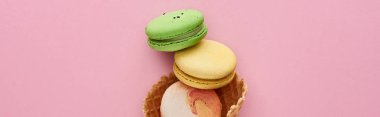 pembe arka plan üzerinde gevrek waffle koni içinde çok renkli lezzetli Fransız macaroons üst görünümü, panoramik çekim