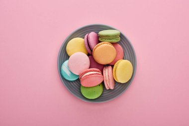 pembe arka plan üzerinde plaka üzerinde çok renkli lezzetli Fransız macaroons üst görünümü