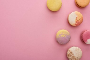 pembe arka plan üzerinde çok renkli lezzetli Fransız macaroons üst görünümü